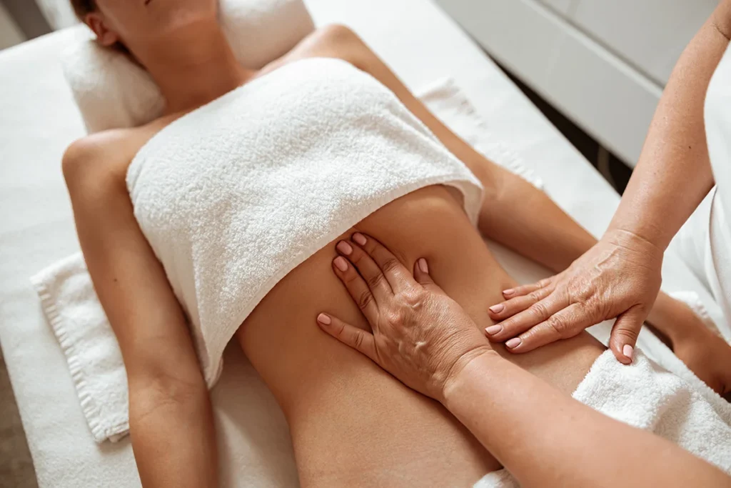 masseuse massaging female client abdomen